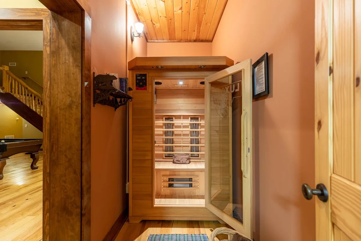 A tranquil infrared sauna room with wooden flooring and soft lighting, creating a serene space for relaxation and self-care after a day of mountain activities.