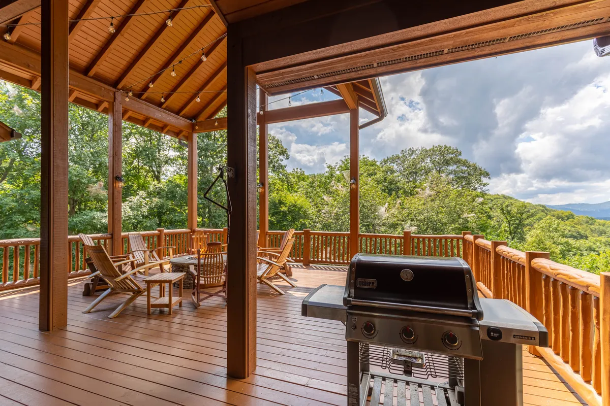 An outdoor grilling and seating area with a view of the surrounding trees, designed for barbecuing, socializing, and enjoying meals outside. The setup is casual but inviting, perfect for informal celebrations or mingling.