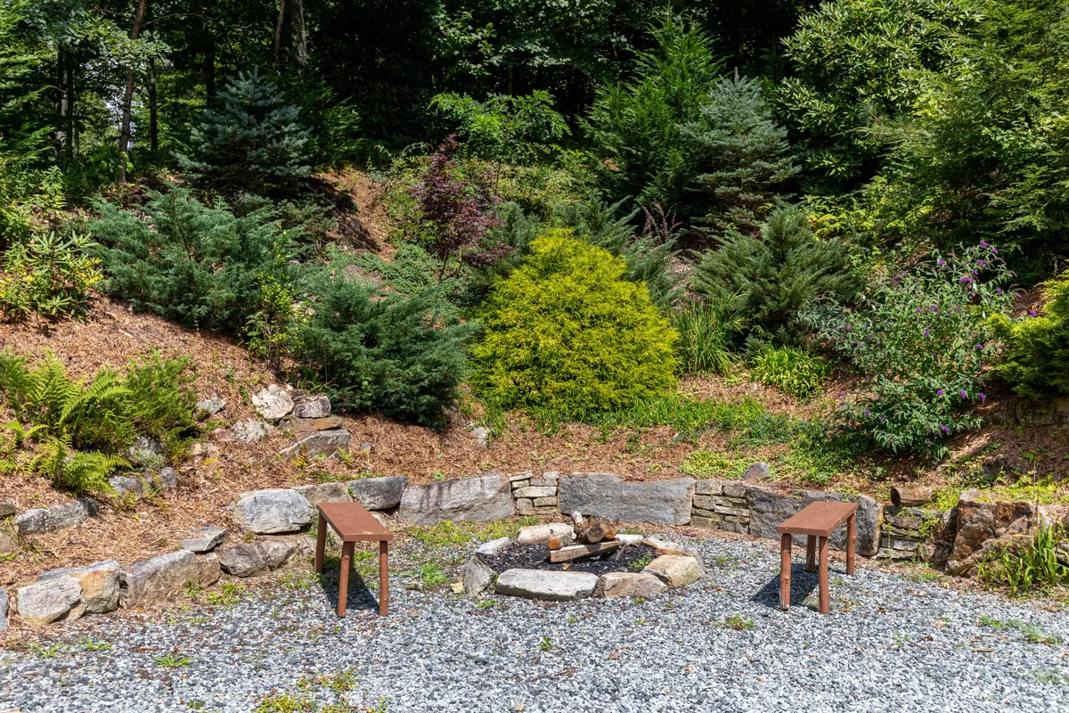 A cozy fire pit with benches arranged in a circle, surrounded by flourishing greenery. The inviting setting is ideal for gathering after a day of exploration or simply enjoying a peaceful evening outdoors.