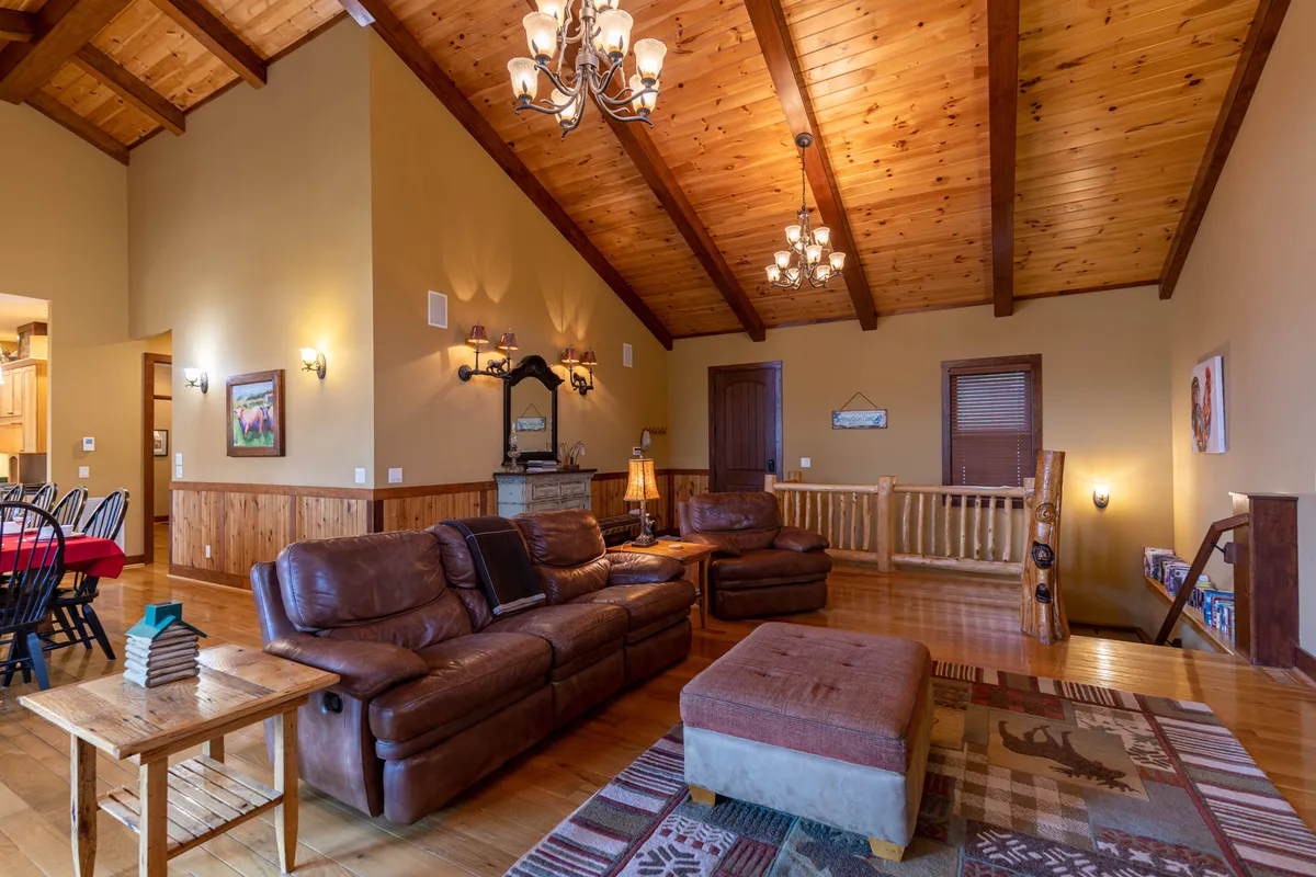 A welcoming living room with leather sofas, wooden coffee table, patterned rug, and a chandelier, all set in a space that feels both social and comfortable. The ambiance invites relaxation and togetherness, echoing the idea of unwinding with family—and pets—after a day outside.