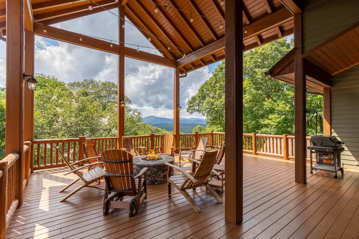 A spacious outdoor seating area featuring a fire pit surrounded by chairs, all set against a stunning mountain view. The scene suggests a welcoming spot for gathering, socializing, and enjoying the natural beauty through all seasons.